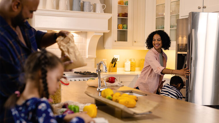 Família reunida na cozinha usando eletrodomésticos modernos, simbolizando o aumento do consumo de energia no Brasil.